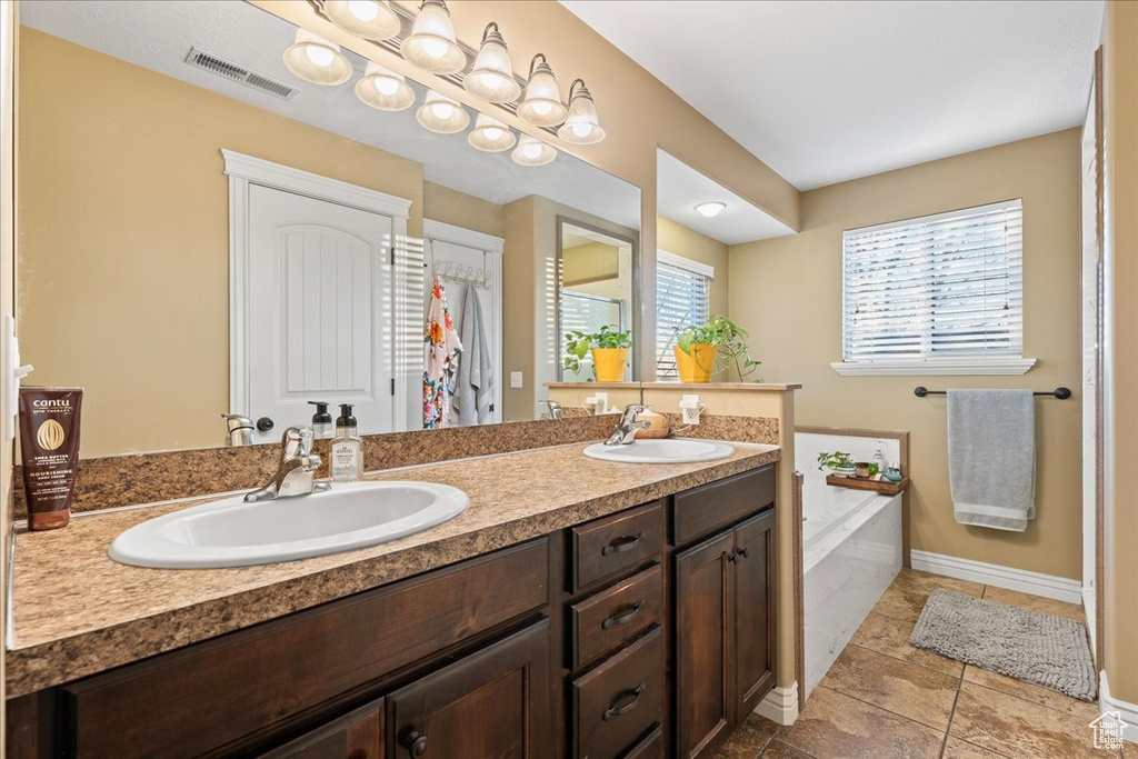 Bathroom with oversized vanity, double sink, a bathing tub, and tile flooring