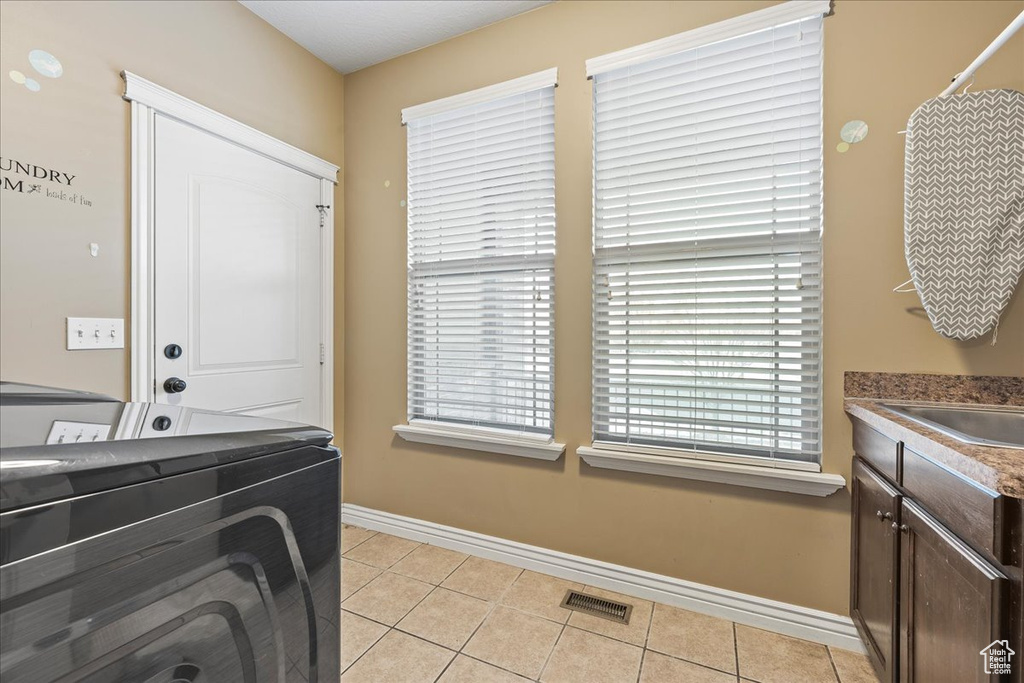 Laundry room with cabinets, sink, washer and clothes dryer, and light tile flooring