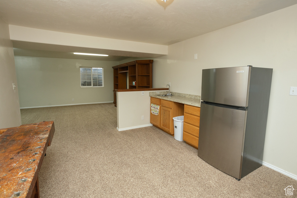 Kitchen with sink, light colored carpet, and stainless steel refrigerator