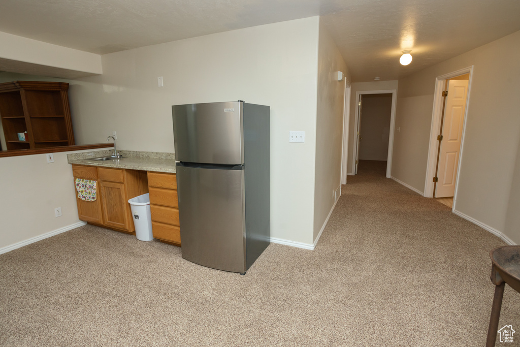 Kitchen featuring sink, light carpet, and stainless steel fridge