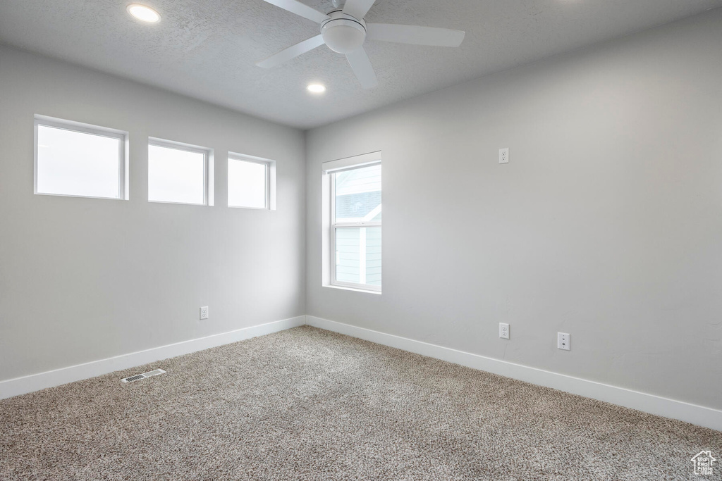 Carpeted empty room featuring a textured ceiling and ceiling fan