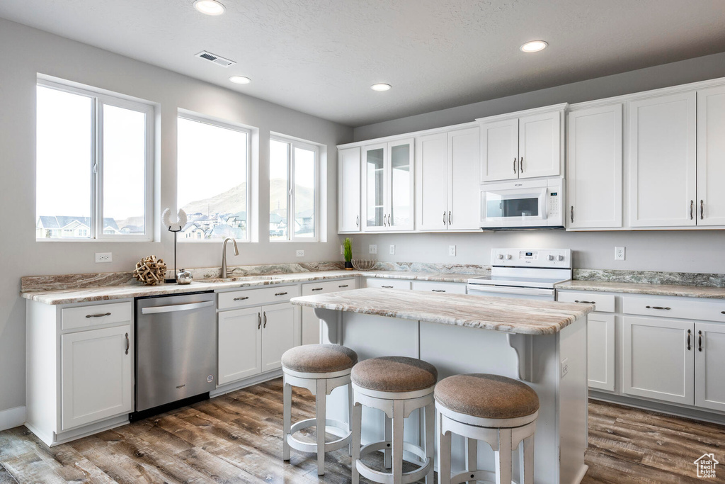 Kitchen featuring white cabinets, white appliances, dark hardwood / wood-style floors, and sink