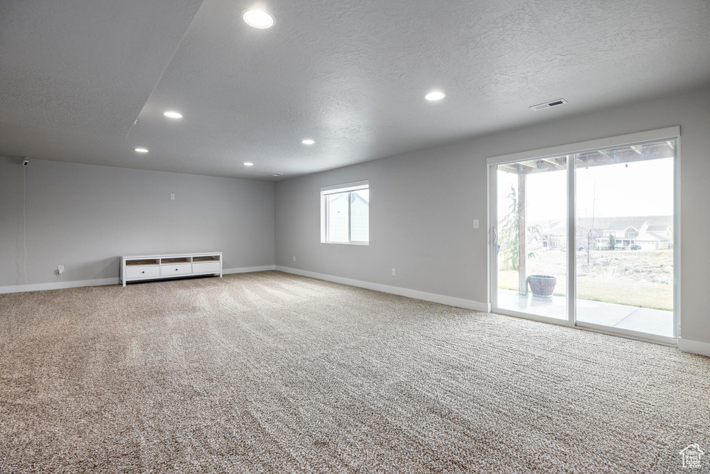 Spare room featuring light colored carpet and a textured ceiling