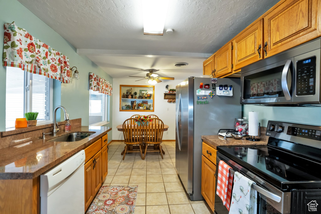 Kitchen featuring stainless steel appliances, a textured ceiling, light tile flooring, sink, and ceiling fan