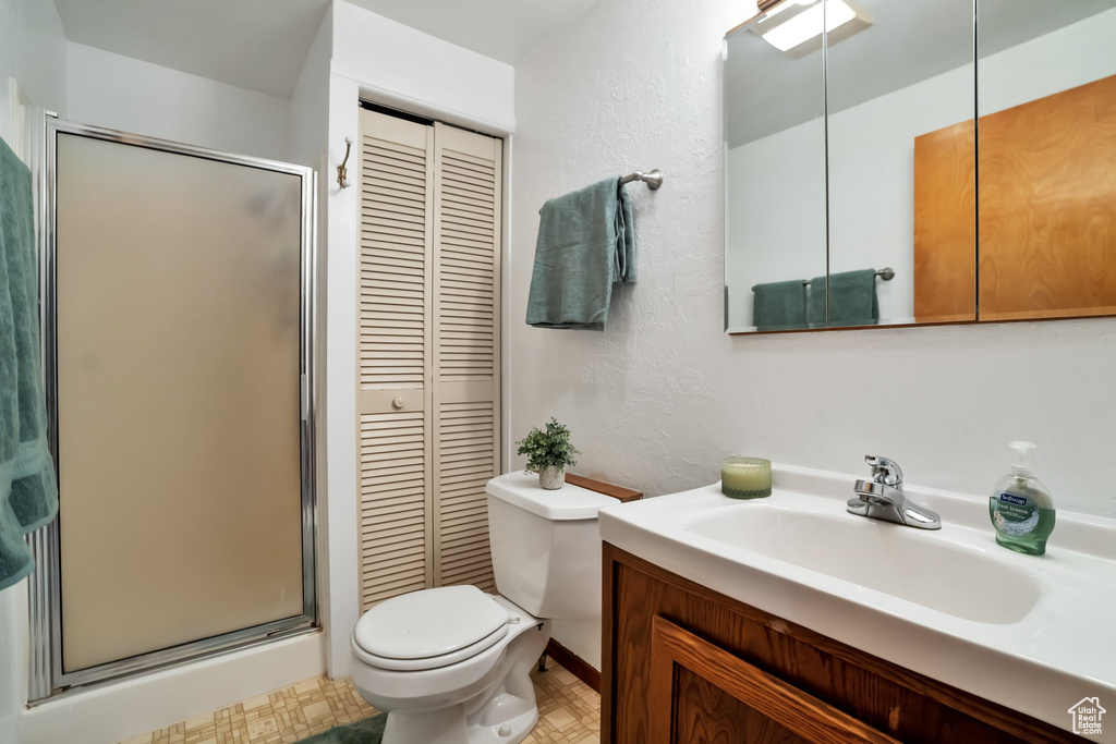 Bathroom with large vanity, tile flooring, walk in shower, and toilet