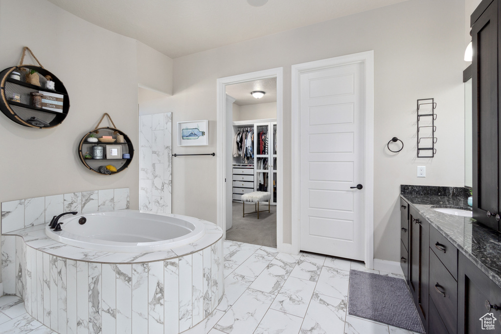 Bathroom featuring vanity, tiled tub, and tile flooring