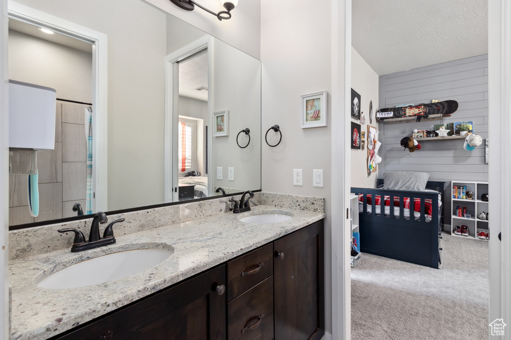 Bathroom featuring dual bowl vanity and a textured ceiling
