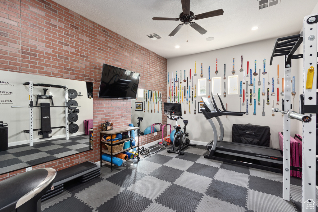 Exercise area featuring brick wall and ceiling fan