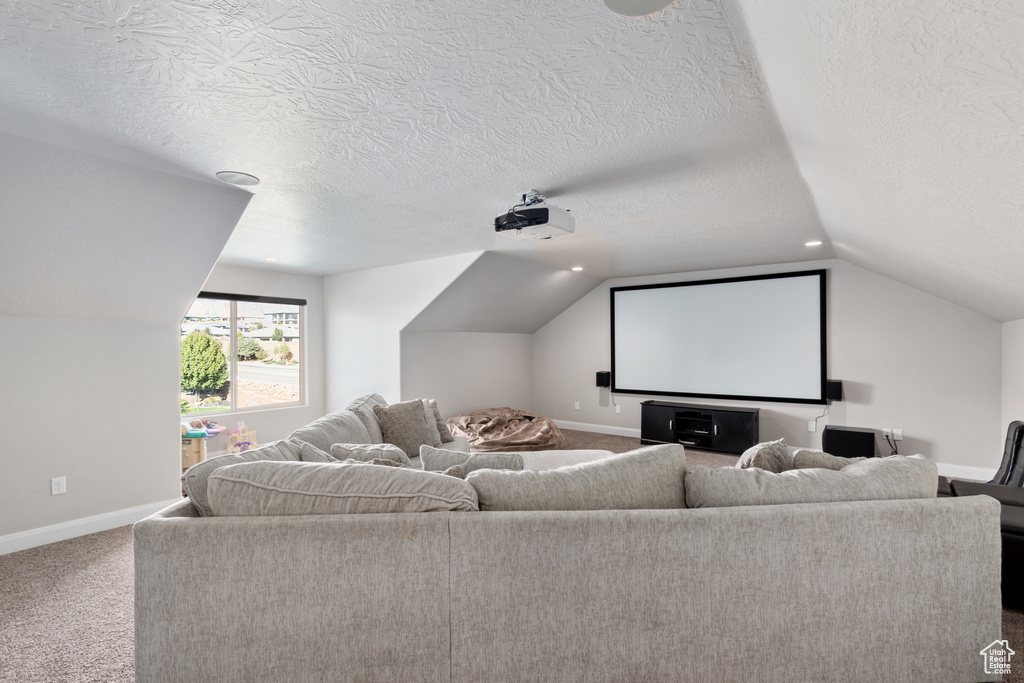 Home theater room with lofted ceiling, a textured ceiling, and carpet