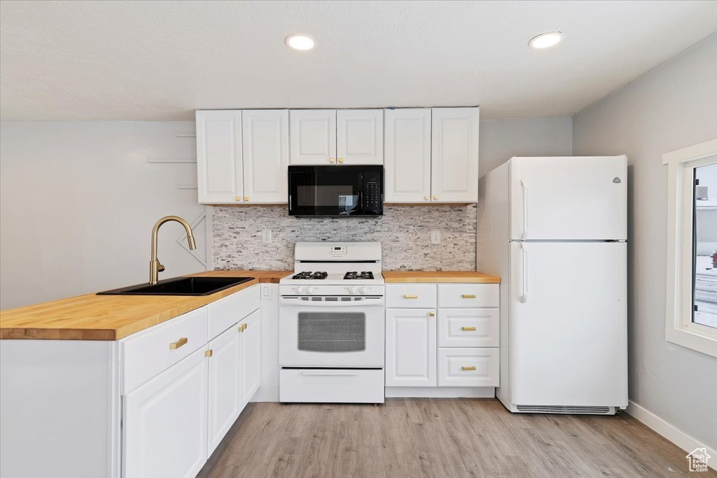 Kitchen with backsplash, light wood-type flooring, white cabinets, sink, and white appliances