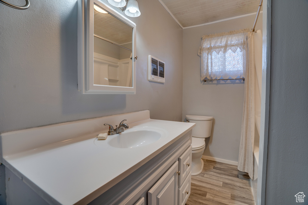 Full bathroom with vanity, shower / bath combo, crown molding, hardwood / wood-style floors, and toilet