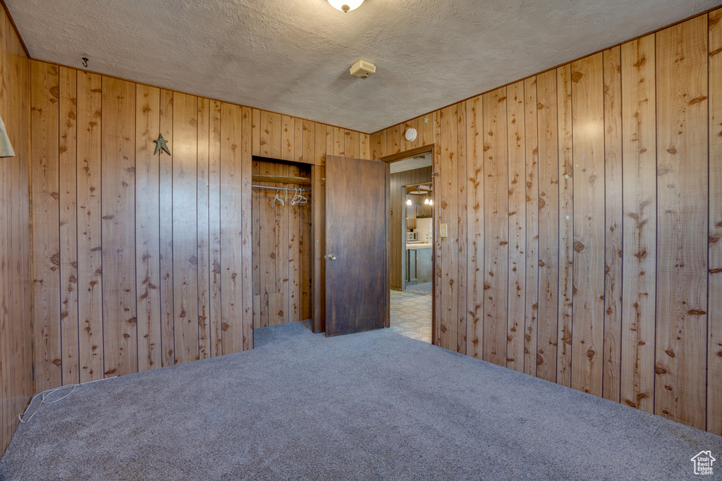 Carpeted spare room with wooden walls and a textured ceiling