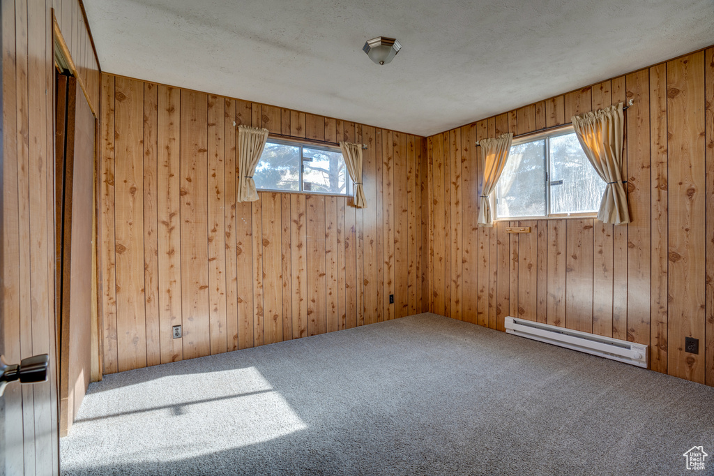 Carpeted empty room with a baseboard radiator and wooden walls