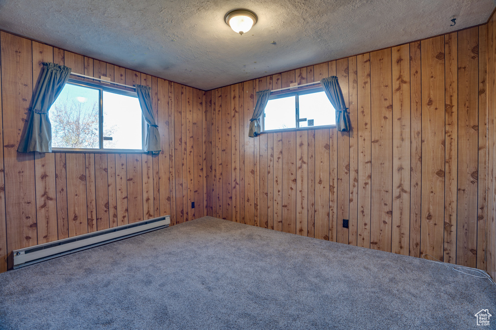 Empty room with baseboard heating, carpet flooring, and a textured ceiling