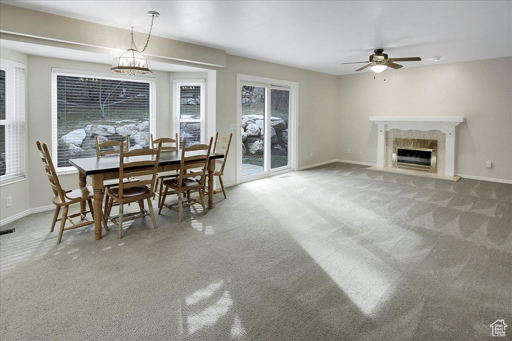 Dining space with light carpet, ceiling fan, and a tile fireplace