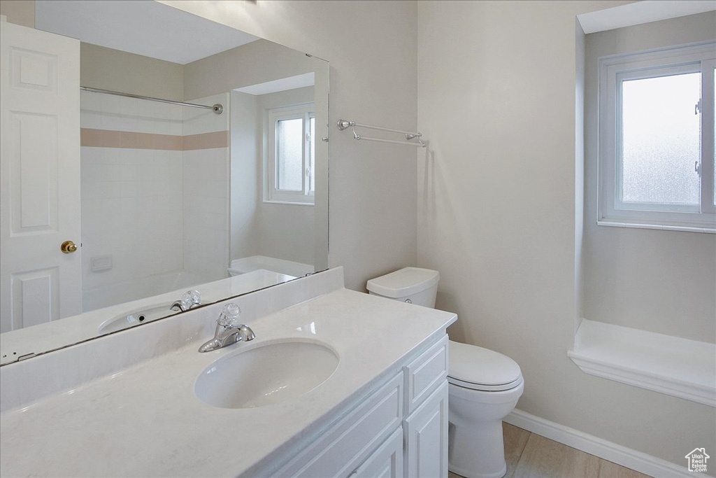 Bathroom featuring a wealth of natural light, oversized vanity, and toilet
