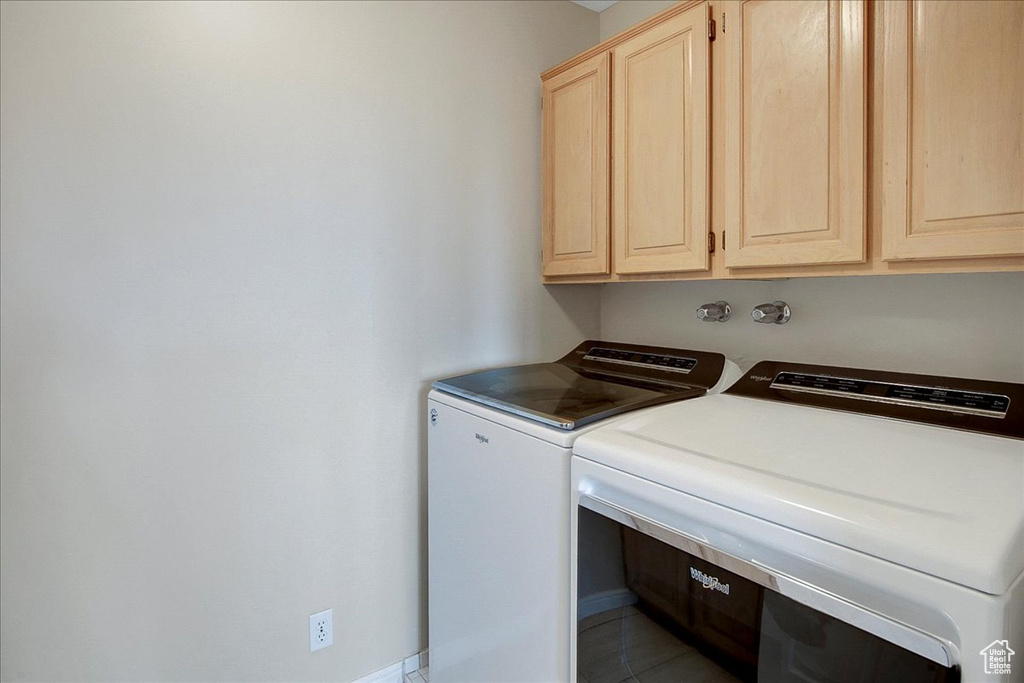 Laundry room with cabinets, light tile flooring, and separate washer and dryer