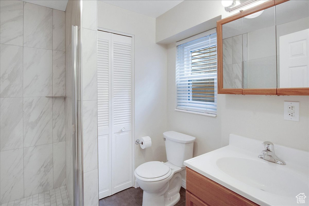 Bathroom featuring vanity, tile flooring, a tile shower, and toilet