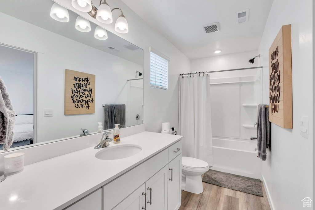 Full bathroom featuring a chandelier, vanity, toilet, shower / bathtub combination with curtain, and wood-type flooring