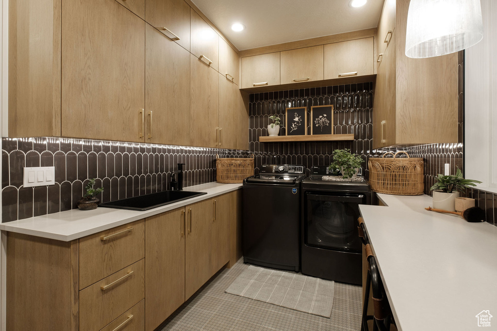 Interior space featuring tasteful backsplash, sink, washing machine and dryer, and light tile floors