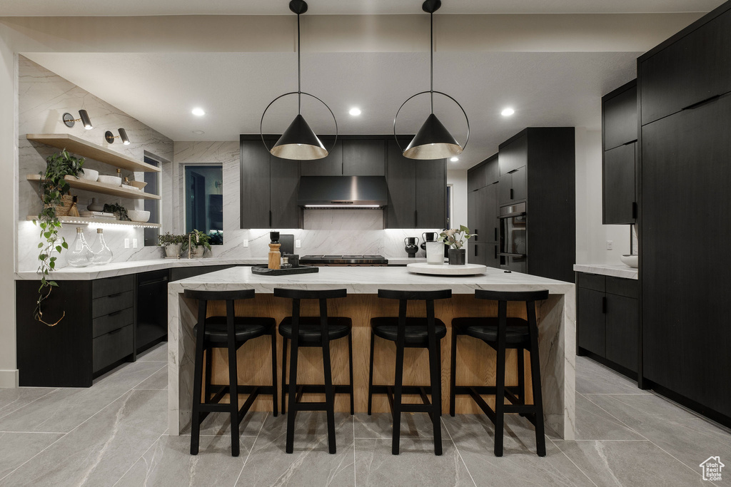 Kitchen with hanging light fixtures, light tile floors, a kitchen island, and backsplash