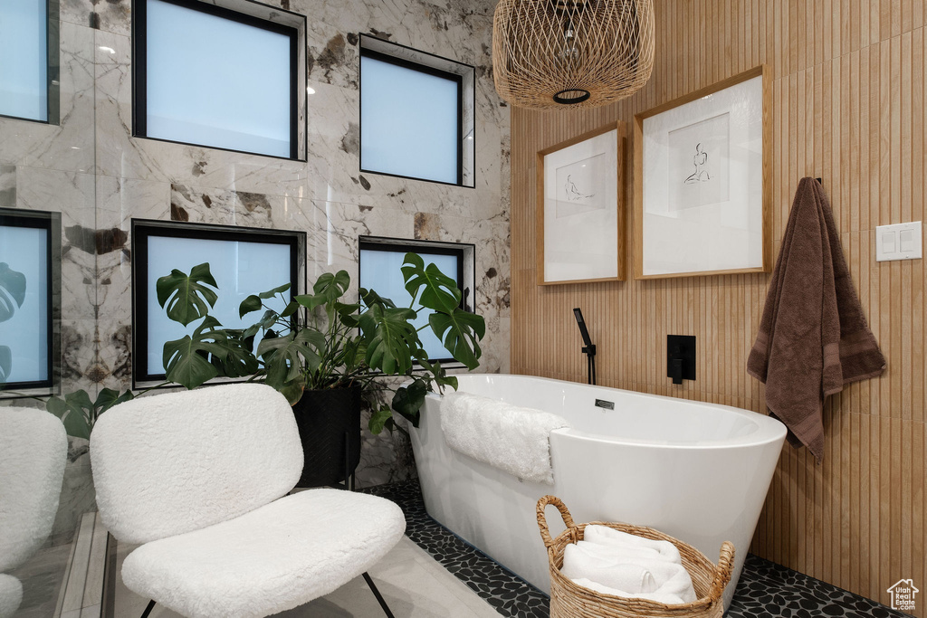 Bathroom featuring a bathing tub, tile walls, and tile flooring