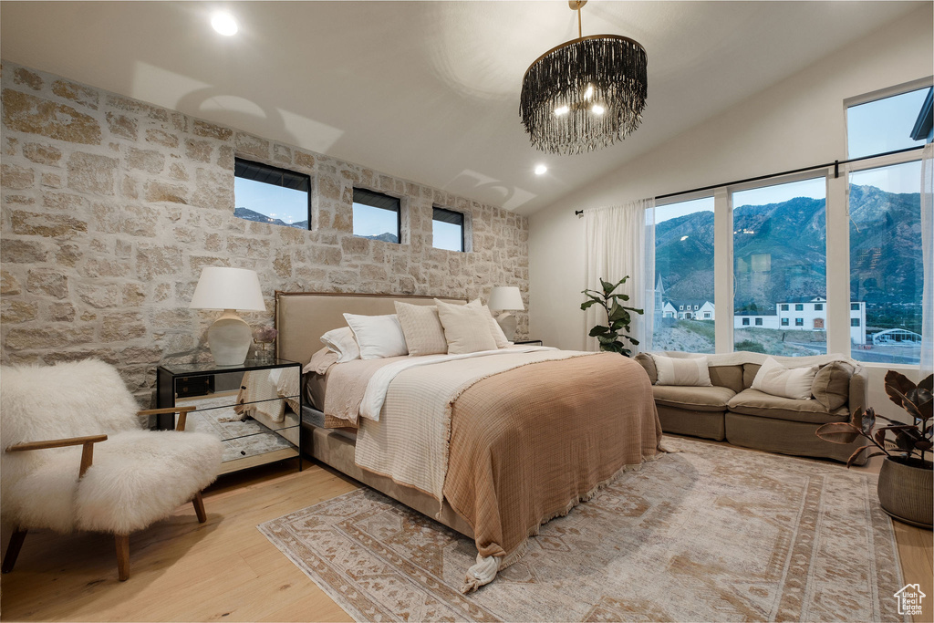 Bedroom with a chandelier, light hardwood / wood-style floors, vaulted ceiling, and a mountain view