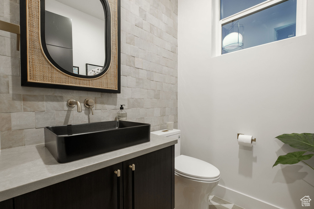 Bathroom featuring oversized vanity, tasteful backsplash, tile walls, toilet, and tile flooring