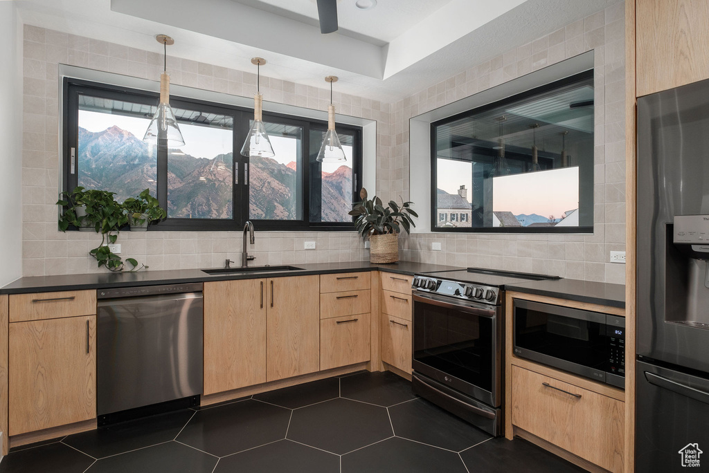 Kitchen featuring a mountain view, tasteful backsplash, sink, pendant lighting, and appliances with stainless steel finishes