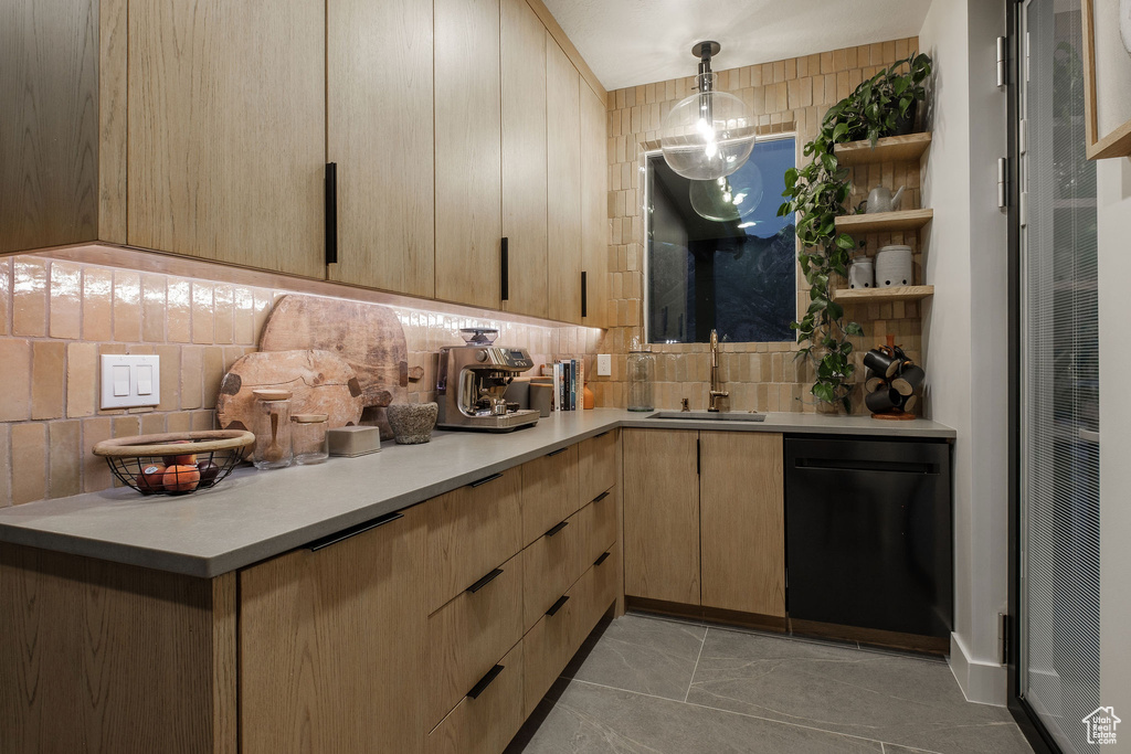 Kitchen featuring pendant lighting, black dishwasher, backsplash, sink, and light tile floors