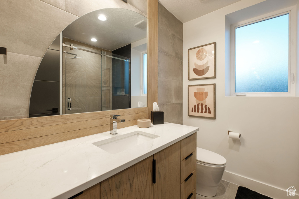 Bathroom featuring a shower with door, tile flooring, oversized vanity, and toilet