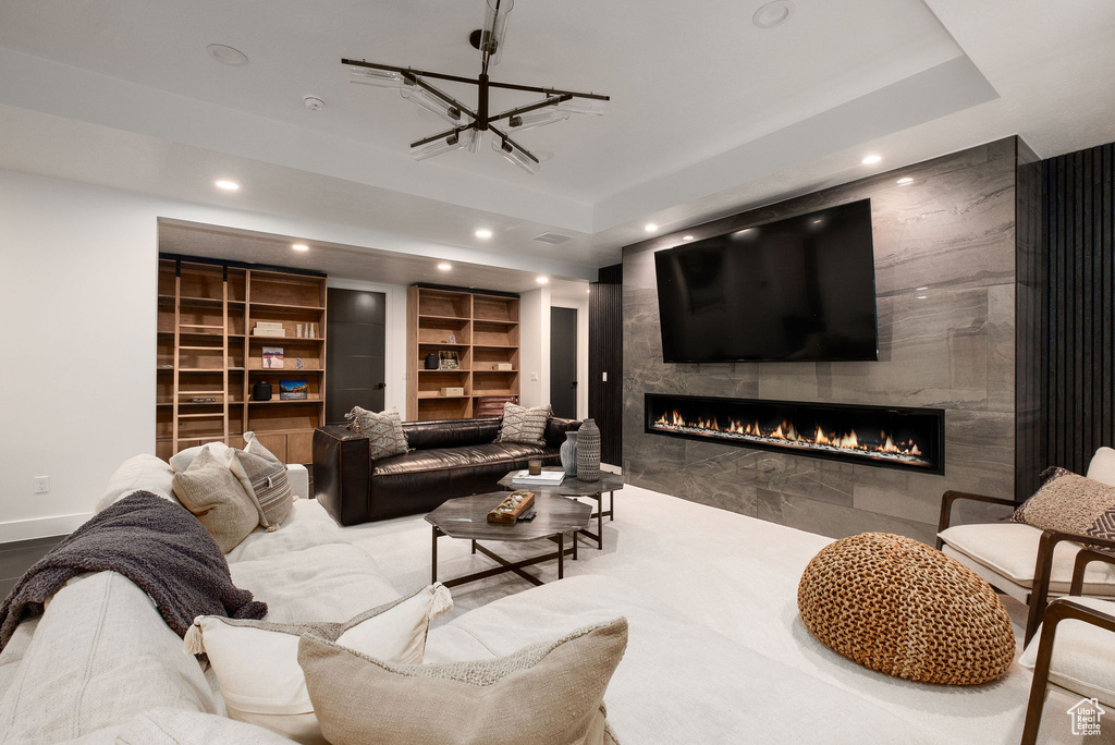 Living room with a tray ceiling, built in features, and a tiled fireplace