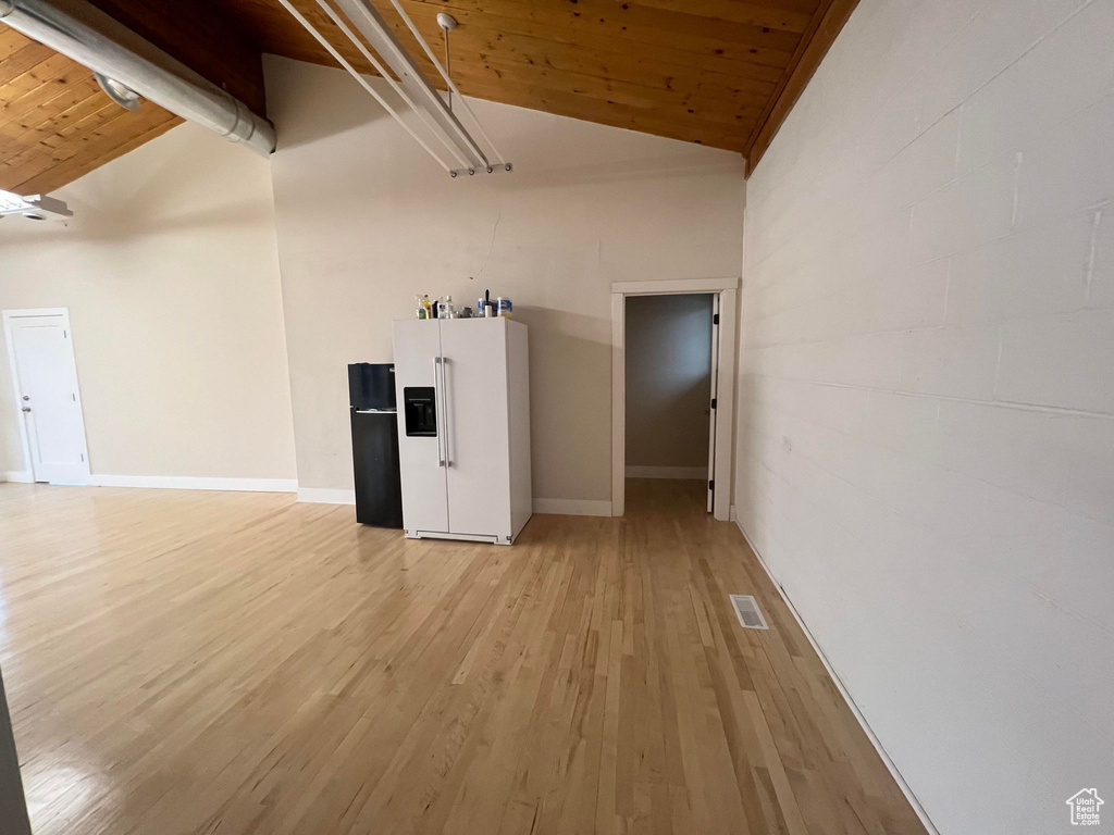 Empty room with wood ceiling, light hardwood / wood-style floors, and vaulted ceiling