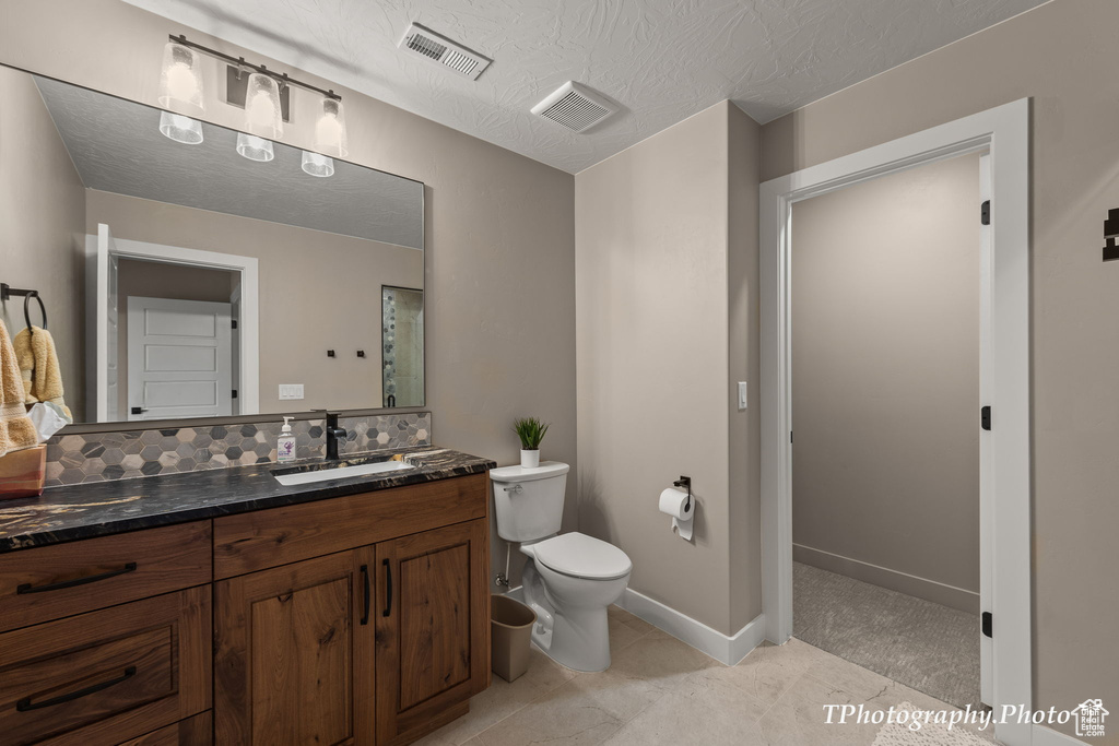Bathroom featuring tasteful backsplash, vanity, tile flooring, and toilet
