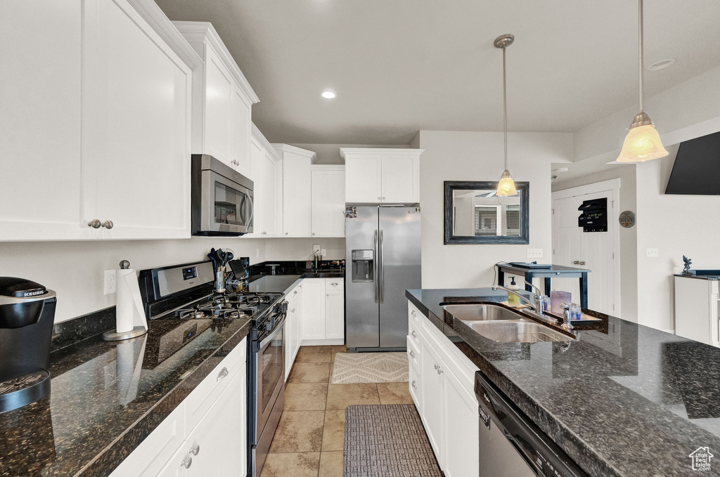Kitchen featuring hanging light fixtures, dark stone counters, stainless steel appliances, and sink