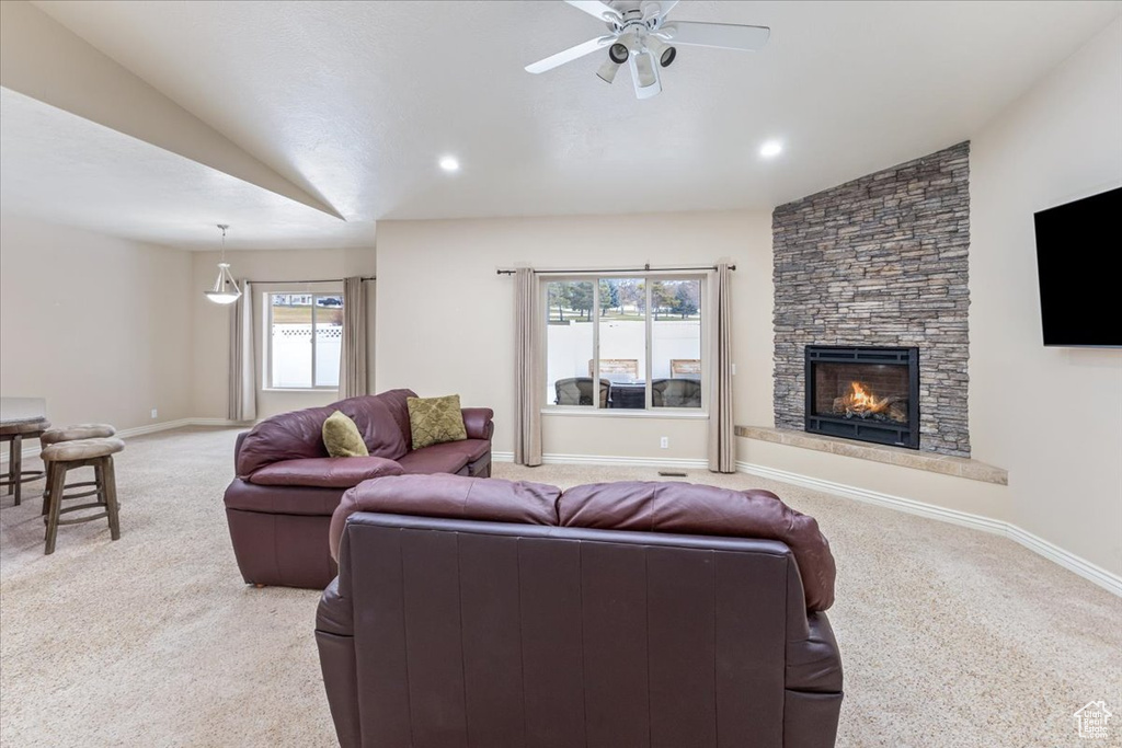 Living room with vaulted ceiling, a fireplace, and a healthy amount of sunlight