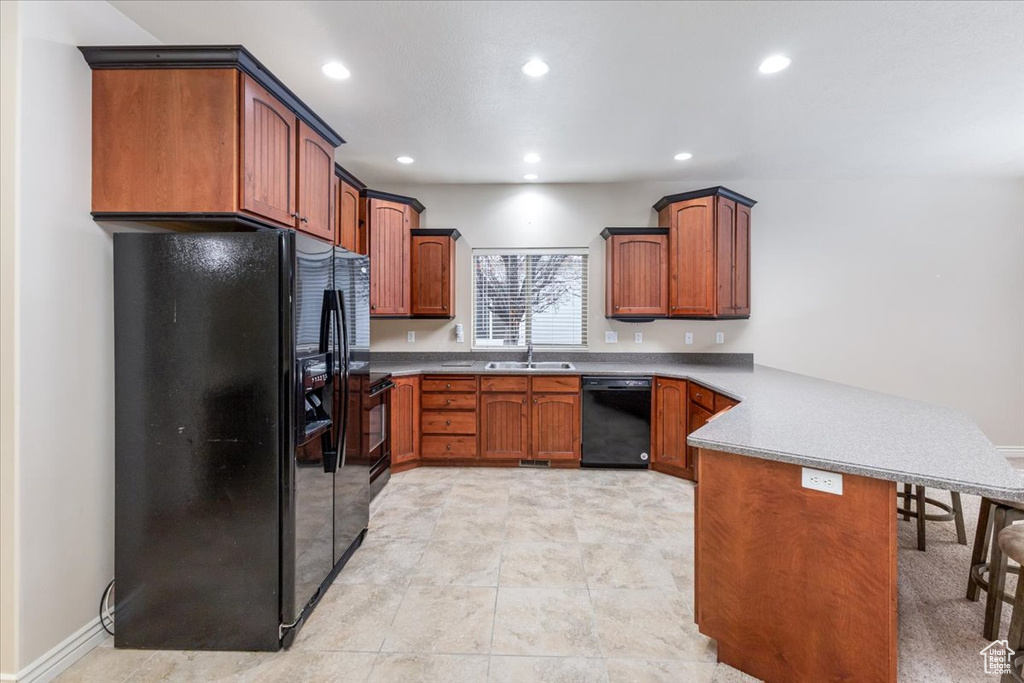 Kitchen featuring sink, black appliances, light tile floors, and kitchen peninsula