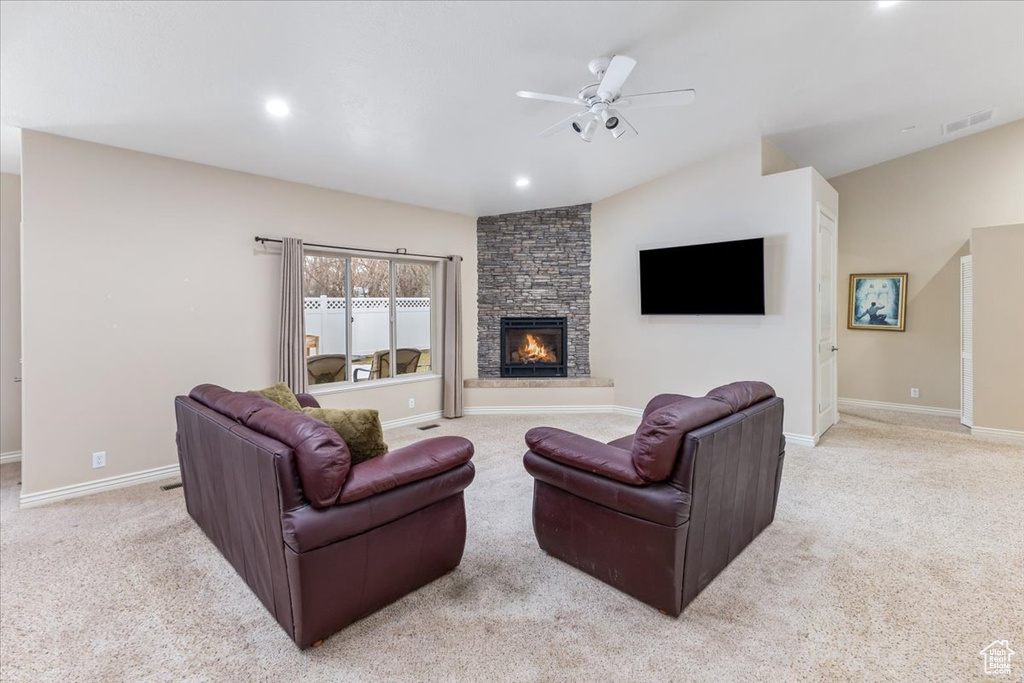 Carpeted living room featuring a fireplace, ceiling fan, and lofted ceiling