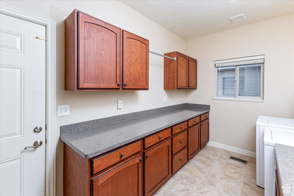 Kitchen featuring independent washer and dryer and light tile floors