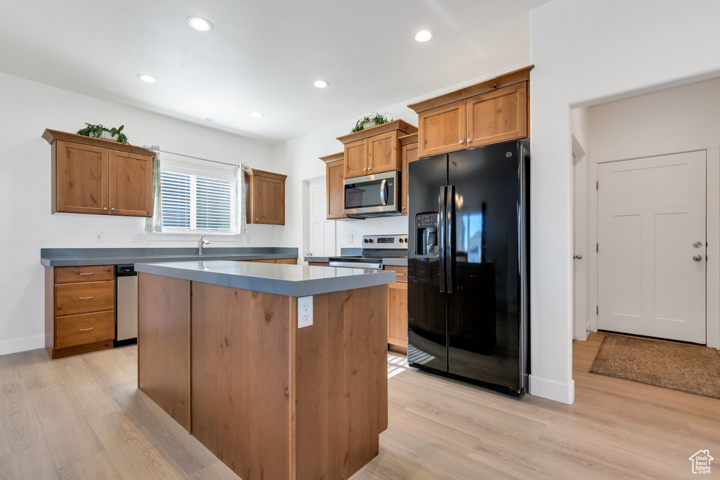 Kitchen featuring light wood-type flooring, appliances with stainless steel finishes, a center island, and sink