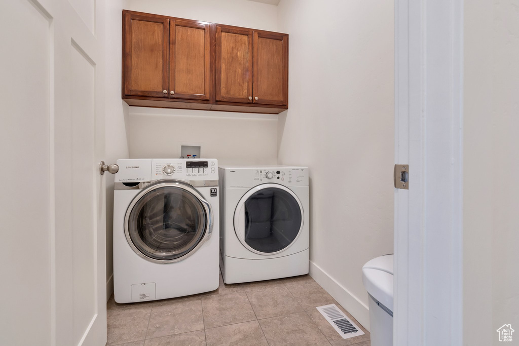 Clothes washing area with cabinets, light tile flooring, independent washer and dryer, and hookup for a washing machine