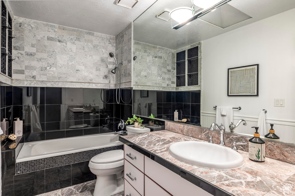 Full bathroom featuring toilet, tiled shower / bath combo, large vanity, and tile flooring