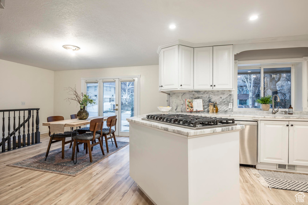 Kitchen with light wood-type flooring, plenty of natural light, stainless steel appliances, and white cabinets