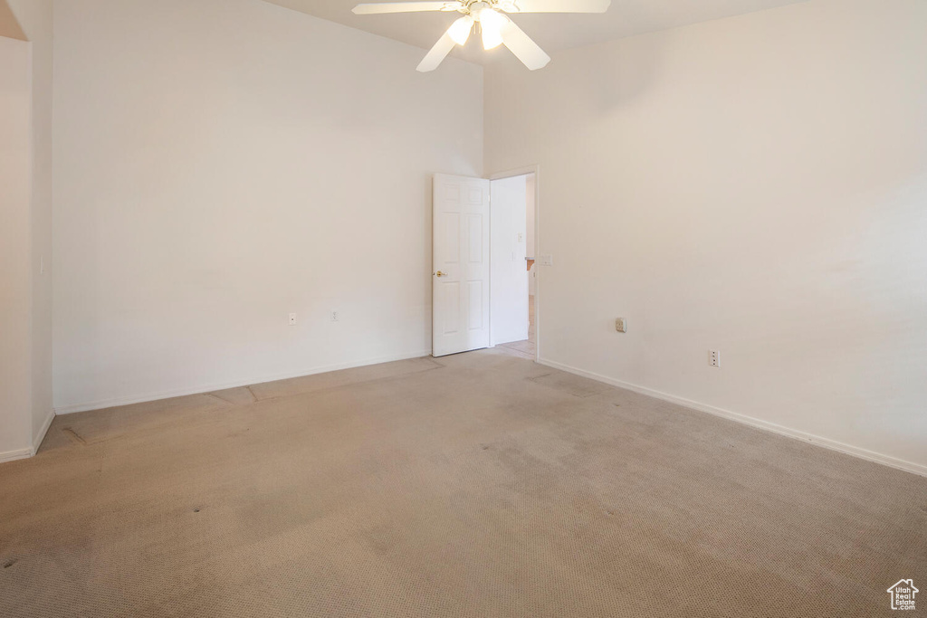 Unfurnished room featuring ceiling fan, light colored carpet, and a towering ceiling