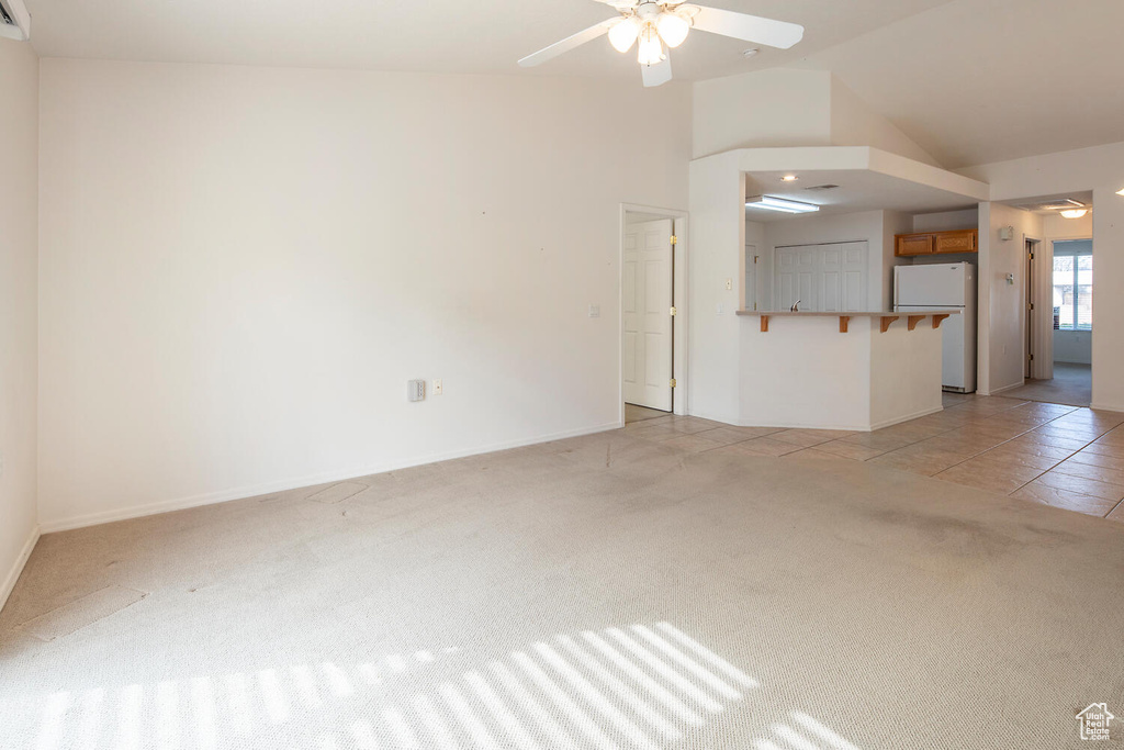 Unfurnished living room featuring high vaulted ceiling, ceiling fan, and light colored carpet