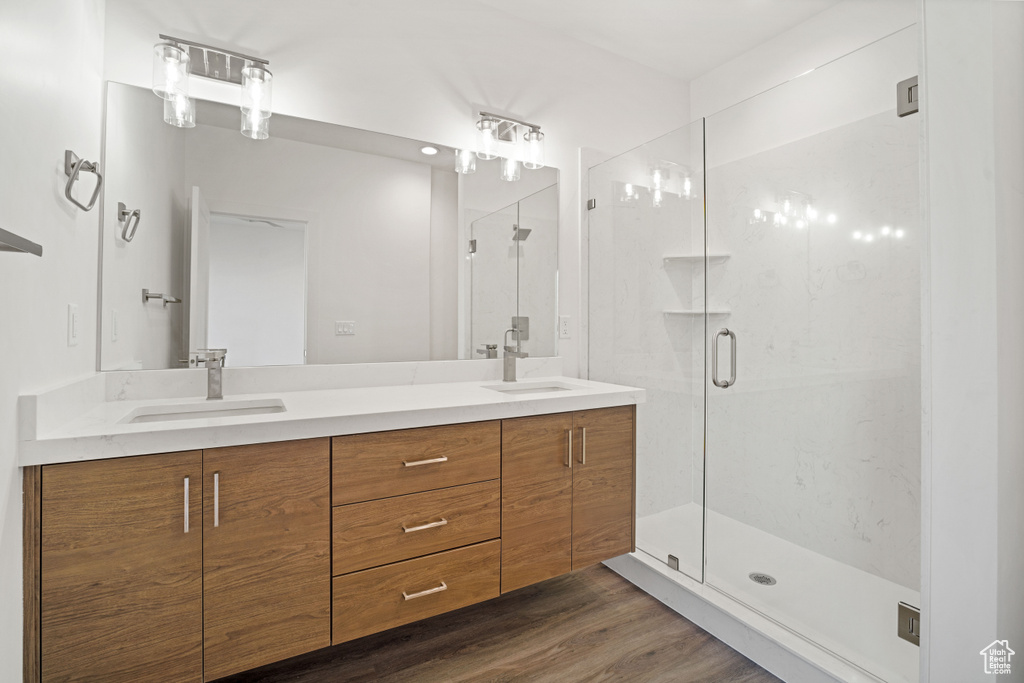 Bathroom featuring hardwood / wood-style flooring, dual bowl vanity, and walk in shower