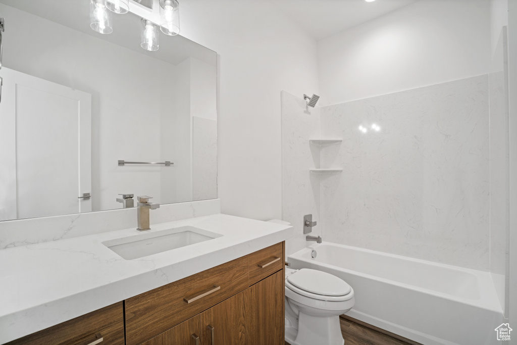 Full bathroom with washtub / shower combination, wood-type flooring, oversized vanity, and toilet