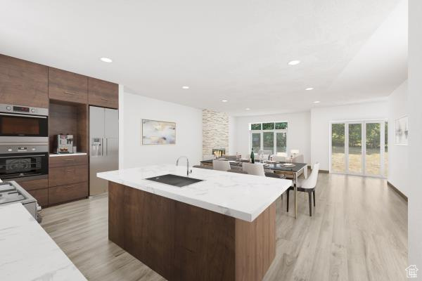 Kitchen featuring white fridge with ice dispenser, double wall oven, sink, light hardwood / wood-style flooring, and light stone countertops