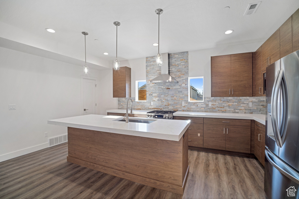 Kitchen featuring backsplash, dark wood-type flooring, sink, stainless steel fridge with ice dispenser, and wall chimney range hood