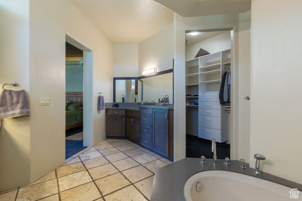Bathroom featuring a tub, vanity, and tile floors